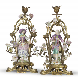 1121.  Pareja de candeleros de estilo rococó de bronce dorado, con figuras galantes de porcelana. esmaltada y flores modeladas. Marca en azul cobalto.Fábrica de Edmé Samson, París, segunda mitad del S. XIX.