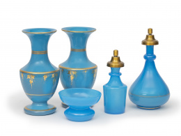 727.  Conjunto en opalina azul parcialmente dorada, formado por: dos frascos, dos floreros y un cuenco.Trabajo francés, tercer cuarto del S. XIX.