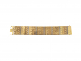 219.  Brazalete articulado en forma de banda ancha en oro biclor con decoración mate