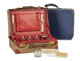 1227.  Neceser de viaje de piel roja con iniciales AG y funda de tela, con maleta azul.Principios del S. XX.