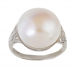 115.  Sortija c. 1920 con media perla abotonada de gran tamaño, y montura decorada con brillantes y decoración calada