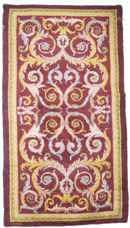 600.  Alfombra en lana de nudo español sobre fondo granate y hojas de acanto.Fábrica de la Cartuja, Burgos, S. XX.
