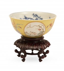 1026.  Cuenco de porcelana esmaltado en amarillo, sobre peana de madera de Huanxu.China, ff. del S. XIX - pp. del S. XX