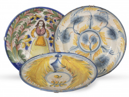778.  Lote de tres platos de cerámica esmaltada, uno con mariposa y otro con decoración esponjada y una dama entre arbustos. Manises, S. XIX.