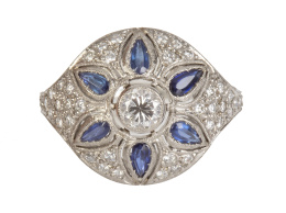 333.  Sortija estilo Art-Decó de frente circular cuajado de brillantes, con chatón central y seis zafiros talla perilla modo de pétalos