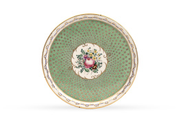 494.  Plato de porcelana esmaltada de verde y dorado con ramillete en reserva. Sévres, ffs. del S. XIX