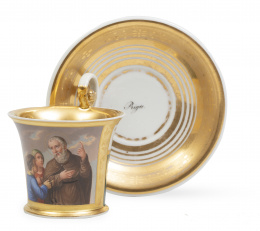 1153.  Taza de porcelana esmaltada, dorada a fuego, con cartela decorativa, con santo. Marcada Riga en el plato.Primer cuarto del S. XIX.