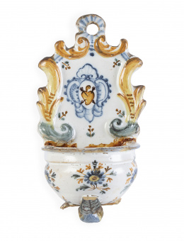 1059.  Benditera de cerámica esmaltada en azul y ocre, con el escudo de las agustinos y decoración floral.Talavera, S. XVIII.