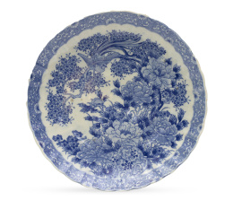 673.  Plato de porcelana esmaltado en azul y blanco con ave y peonías.Japón, S. XIX.