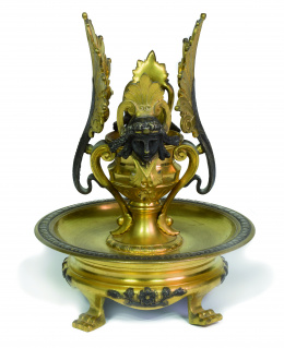 1186.  Candelero de bronce dorado y patinado, con palmetas y cabezas a los lados.Trabajo francés, ffs. del S. XIX..