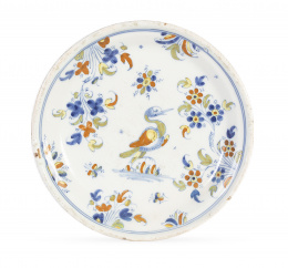 1120.  Plato de cerámica esmaltada, en azul, ocre, manganeso y naranja, decorada con ave de la serie de chinescos.Alcora, primera época (1735-1760).