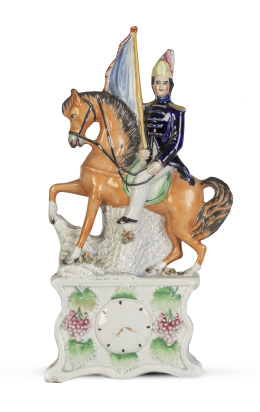 1191.  Soldado con bandera a caballo, sobre base con reloj.Figura de loza esmaltada.Staffordshire, Inglaterra, S. XIX.