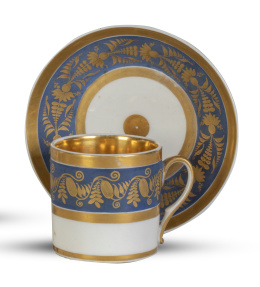 1341.  Taza con plato de porcelana esmaltada y dorada con friso con fondo azul.Francia, h. 1800.