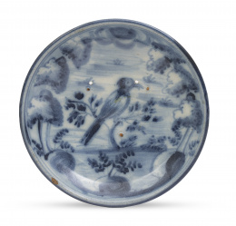 1196.  Plato de cerámica esmaltada en azul y blanco con ave entre 