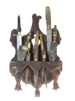 1191.  Conjunto de nueve puñales y navajas, en hueso, metal y ébano. En un soporte de madera.Albacete, S. XIX.