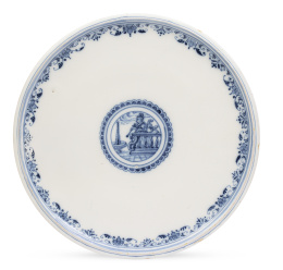 1235.  Plato de cerámica esmaltada en azul y blanco con medallón con personaje, perro y fuente en el asiento.Alcora, serie Berain (1727-1749).