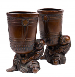 468.  Pareja de copas en bronce pavonado cuyo recipiente es sostenido por dos monjes.Japón, XIX