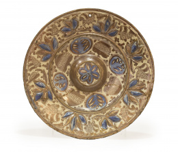564.  Plato con umbo de cerámica esmaltada en reflejo dorado y azul, con piñas, flores y hojas en relieve.Manises, S. XVII.