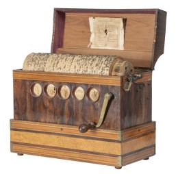 1255.  Órgano Serinette con caja de madera de nogal y con cartela en el frente con incrustación metálica que reza: "G. giachetti Cigliano"h. 1925.Con un rodillo de madera