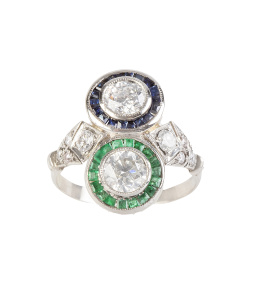 396.  Sortija lanzadera tu y yo estilo Art-Decó, con dos ojos de perdiz con centro de brillante de 0,80 ct cada uno, uno con orla de esmeraldas y otro con orla de zafiro