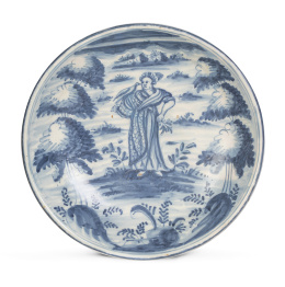 1145.  Plato de cerámica esmaltada en azul de cobalto, con una dama con un ave, flanqueada por árboles de pisos.Talavera, S. XVIII.
