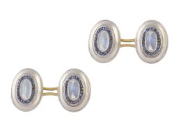 76.  Gemelos dobles Art Decó ovales con cabuchónes pan de azucar de piedras luna,  orlados de zafiros calibrados y marco oval liso