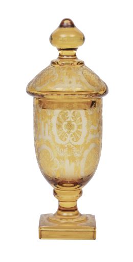 724.  Copa con tapa de cristal ámbar con decoración grabada con ciervos y arquitecturas.Bohemia, finales del S. XIX - principios del S. XX.