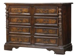 1081.  Cómoda de madera de nogal, con decoración tallada de niños con hojas y frutos a cada lado y tiradores de hierro.Trabajo lombardo, S. XVII.