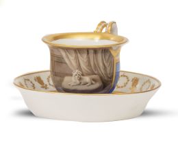 672.  Taza con su plato de porcelana esmaltada y dorada, con perro sobre almohadón. Marca en azul en la base.Viena, S. XIX.