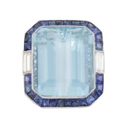 411.  Sortija con gran aguamarina central talla esmeralda, en marco de zafiros calibrados flanqueado por diamantes talla baguette