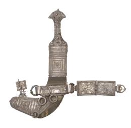 1125.  Jambiya en acero, tela y vaina en plata con decoración en relieve, con ajustes para cinturón.Yemen, S. XIX.
