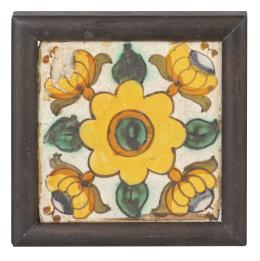 725.  Azulejo de cerámica esmaltada en verde, amarillo y manganeso decorado con flores. Con marco.Cataluña, S. XVIII.