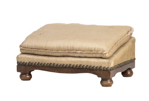 Reposa piés de madera tallada, tapizado en beige y tachonad