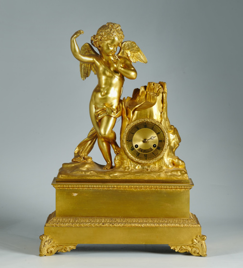 Reloj en bronce dorado con un “putto” apoyado a un tronco.