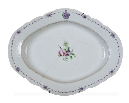 Bandeja oval de porcelana esmaltada con flores y un blasón.