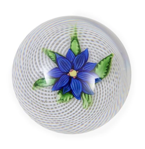 Pisapapeles con flor azul sobre retícula en blanco. Clich