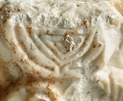 Capitel romano en mármol tallado, con una Menorah o candela