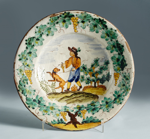 Plato de cerámica esmaltada, con un personaje con un perro 