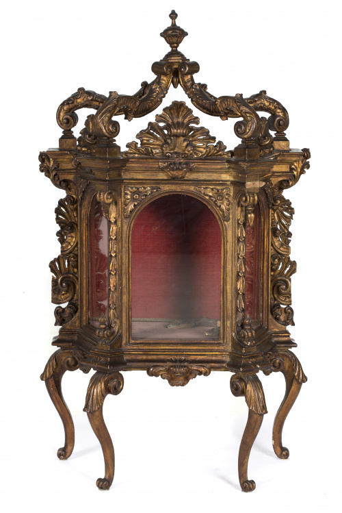 Vitrina de madera tallada y dorada, con tornapuntas en “c”.