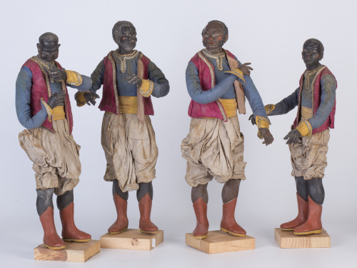 Cuatro figuras de personajes negros de madera tallada y pol