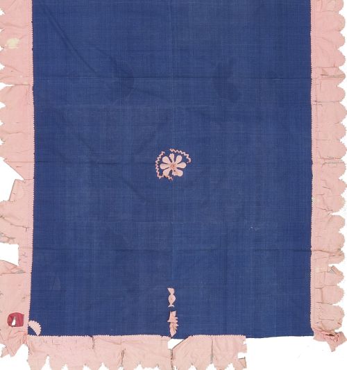 Colcha de tela azul con cenefa y flor en el centro en rosa.