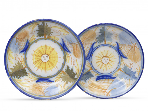 Pareja de platos de cerámica esmaltada con soles en el asie