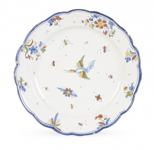 Plato de cerámica esmaltada con ave, en azul, ocre y rojo.
