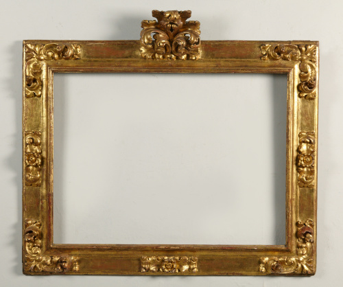 Marco en madera tallada, estucada y dorada, con copete.Tra