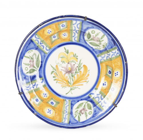 Plato de cerámica esmaltada, con flor y cartelas en el aler
