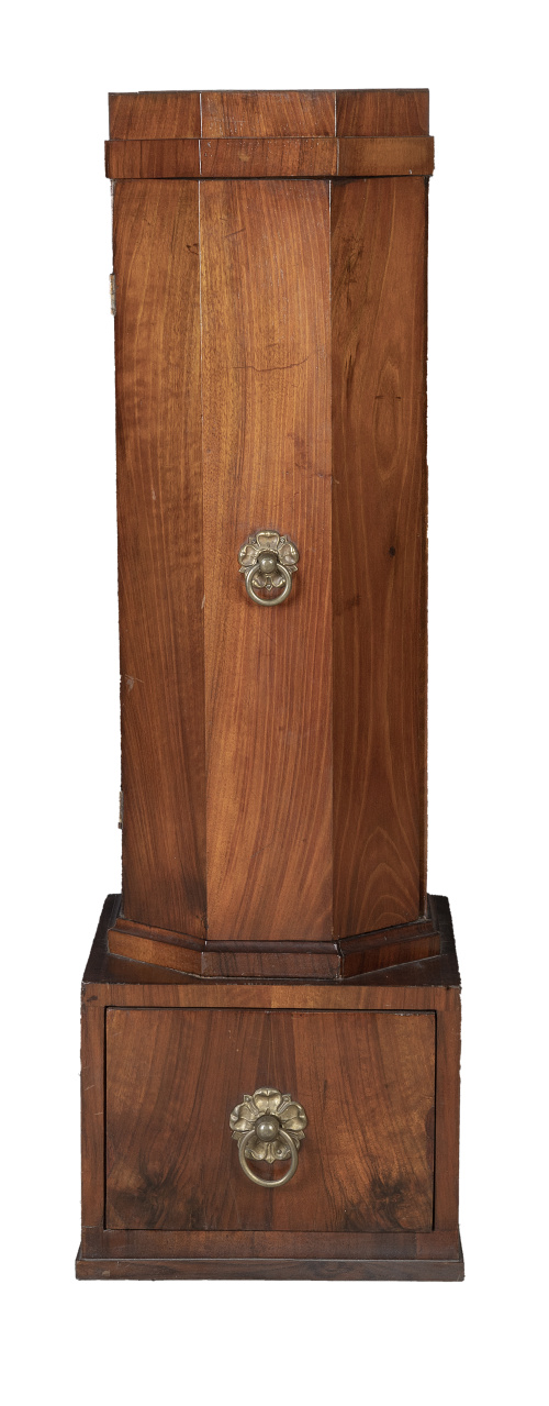 Armarito bajo con forma de columna para guardar sombreros.