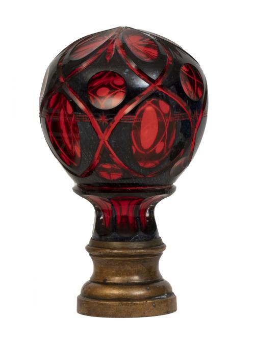 Remate de escalera de cristal granate sobre base de metal.