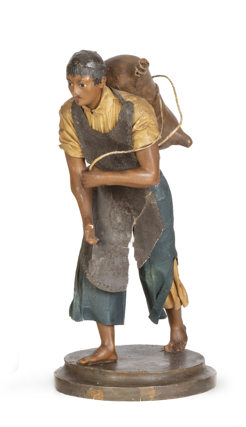 Figura de cera policromada, textil y saco de barro policrom